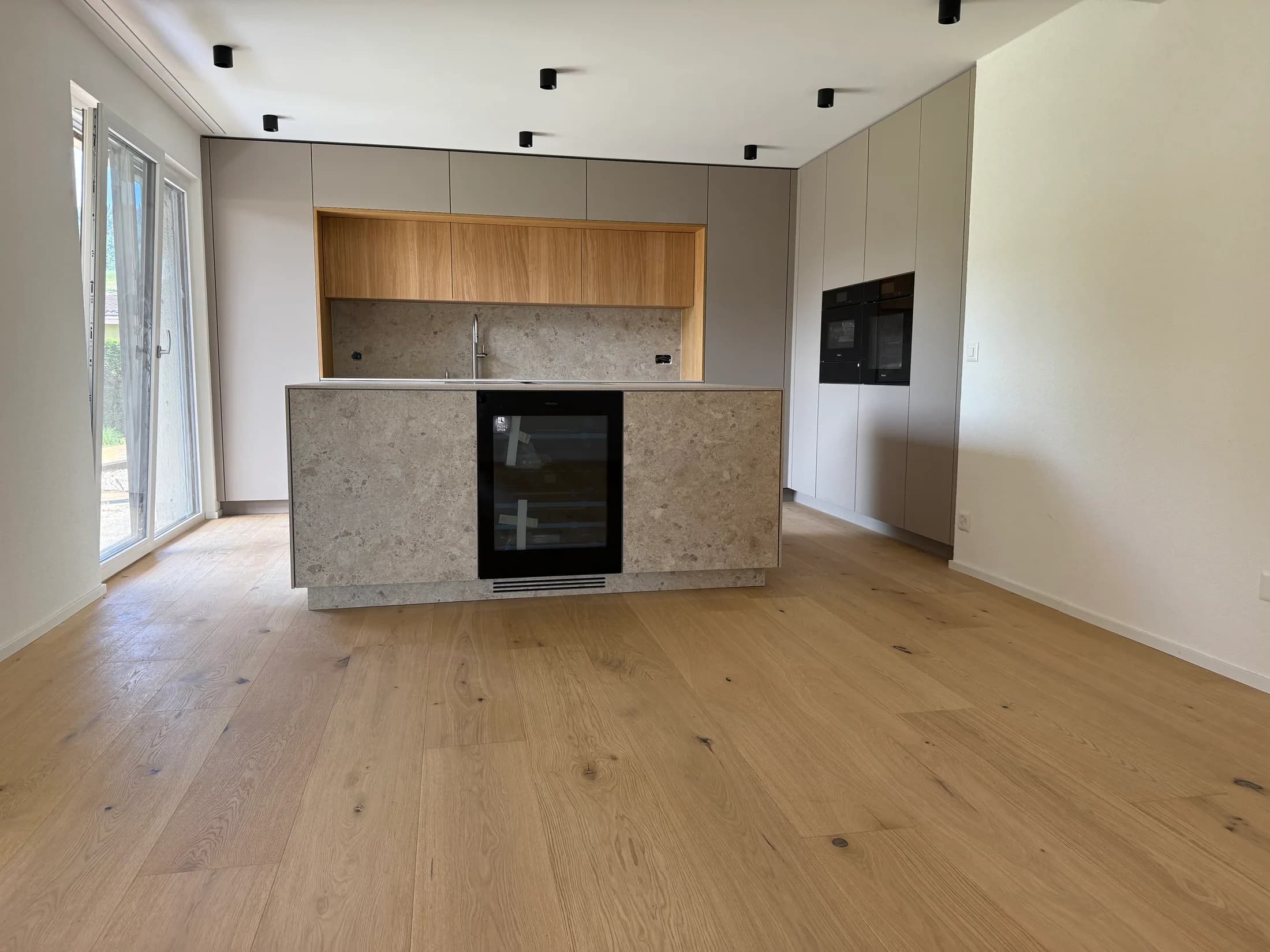Offene Küche mit Natursteininsel und ruhig verlegtem Eichenparkett