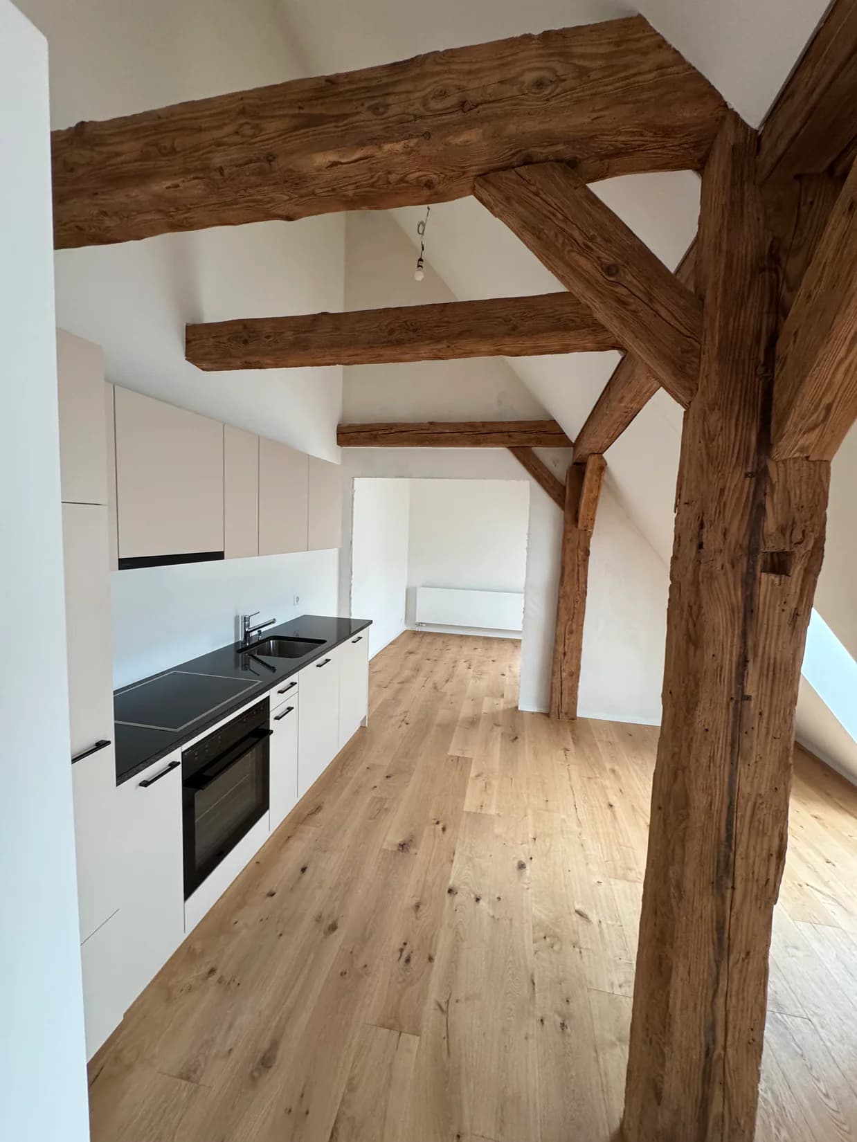 Natürliche Eichen-Landhausdielen in einer Dachwohnung mit sichtbaren Holzbalken