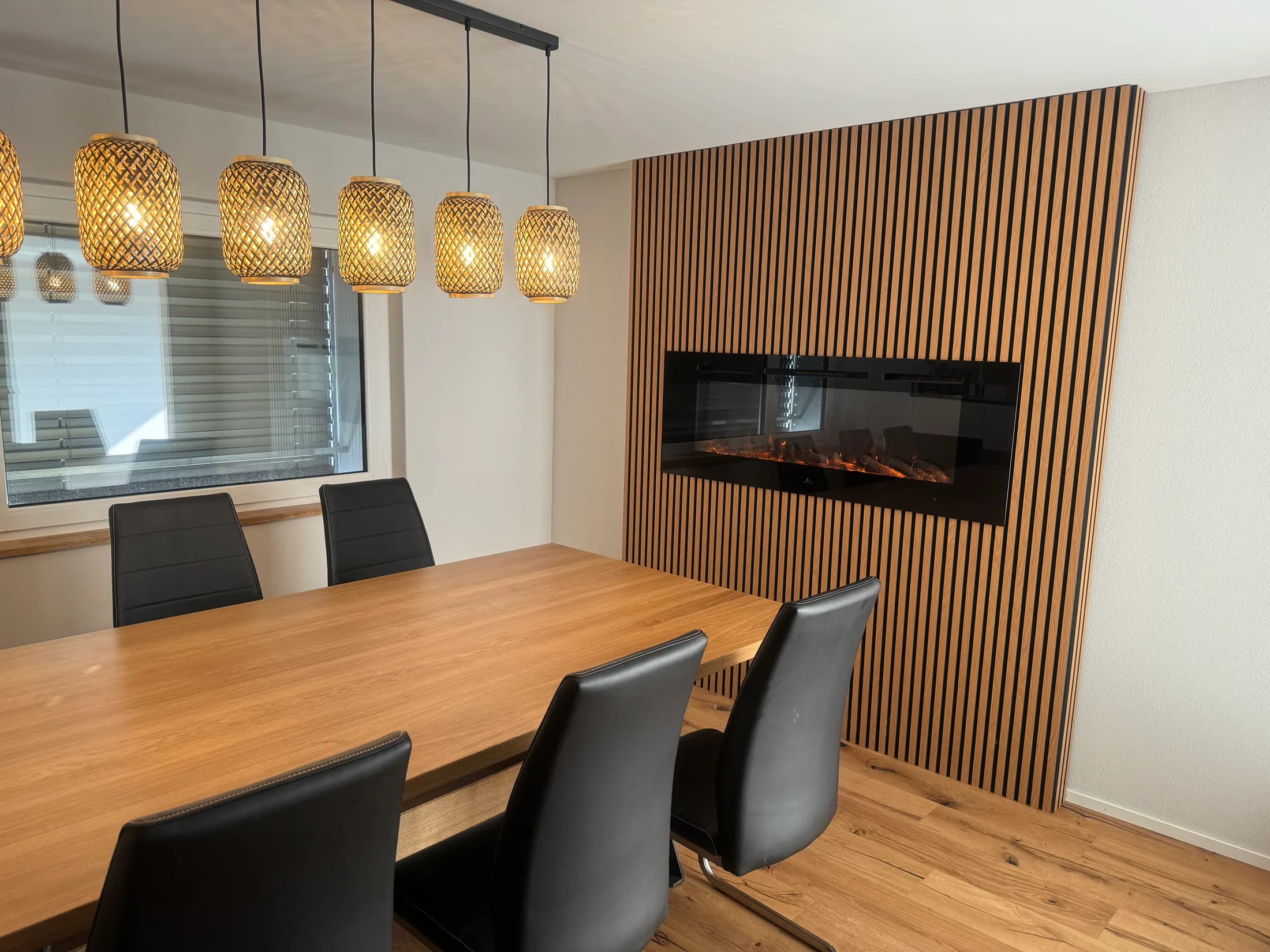 Esszimmer mit Eichenparkett, Holzlamellenwand und moderner Beleuchtung